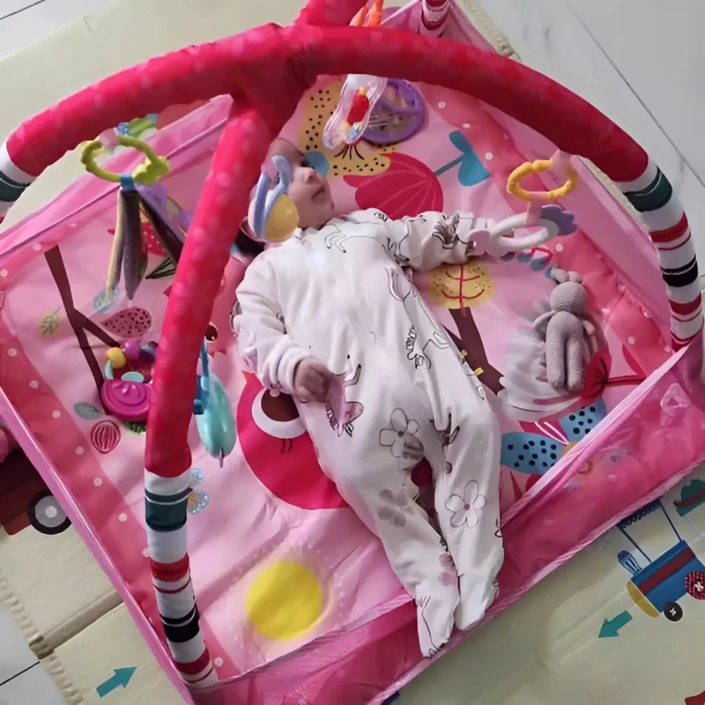 Bébé jouant sur un tapis sensoriel rose musical avec jouets suspendus, stimulant l'éveil et l'amusement.